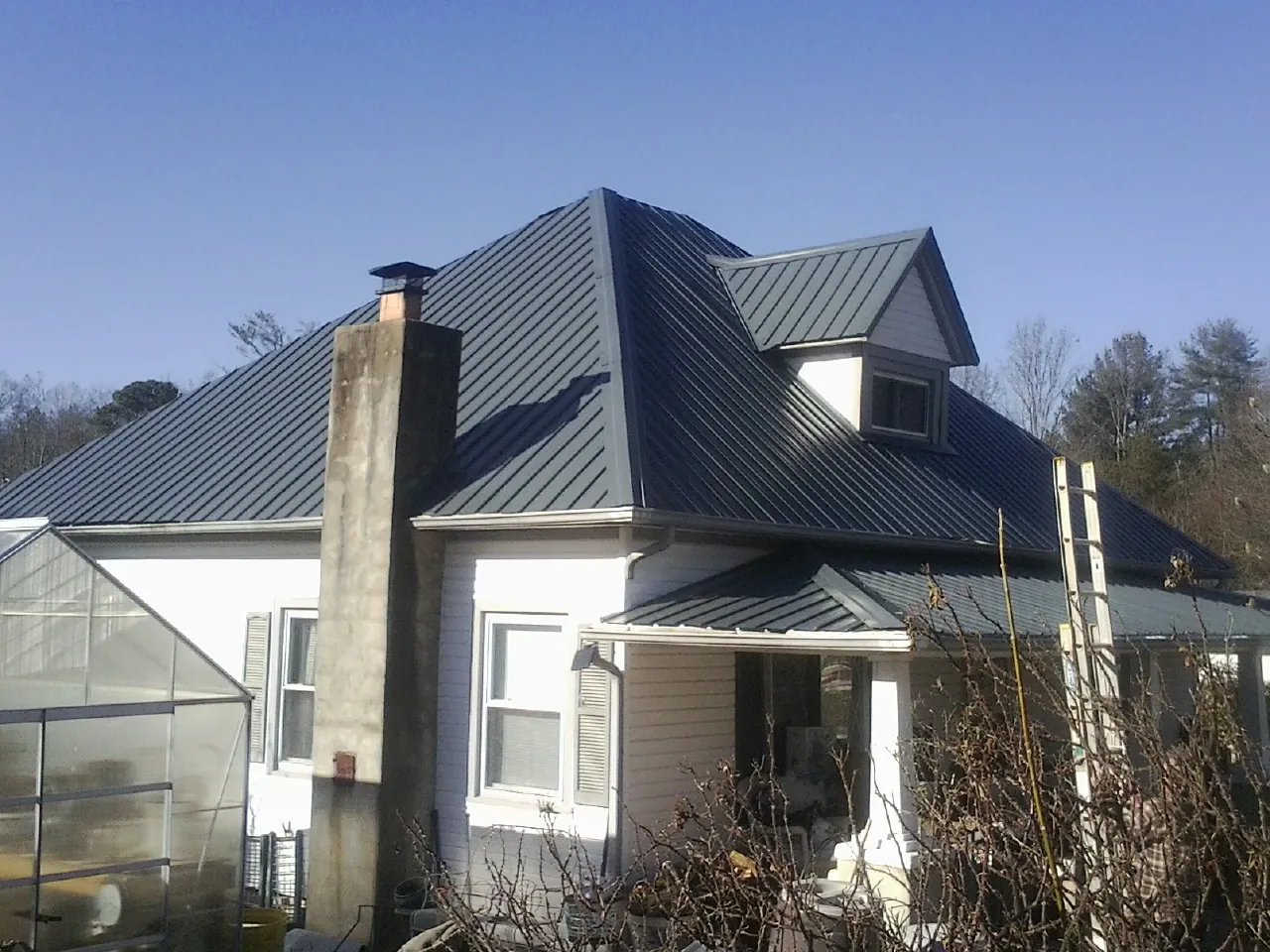 Dark blue standing seam metal roof on a white farmhouse with dormer — Slate & Tile Roof Repair by Roofing Brothers in Castleford