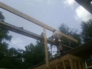 Carpenter setting a ridge beam over a new addition frame — Ice Dam Removal by Roofing Brothers in Castleford