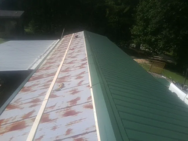Old rusted panels beside newly installed green metal roofing — Wind Damage Roof Repair by Roofing Brothers in Castleford