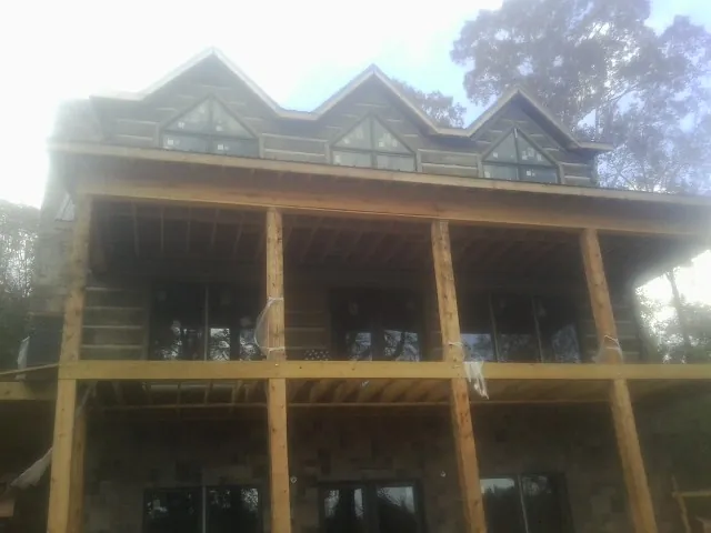 Dormers and porch framing on a large log home under construction — Roof Coating work by our crew in Castleford
