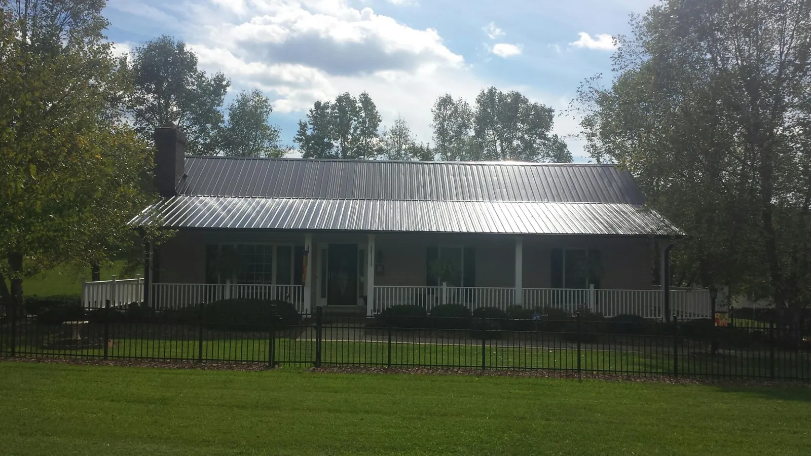 Gray metal roof on a brick ranch with a full width front porch — Gutter Guard Installation work by our crew in Castleford