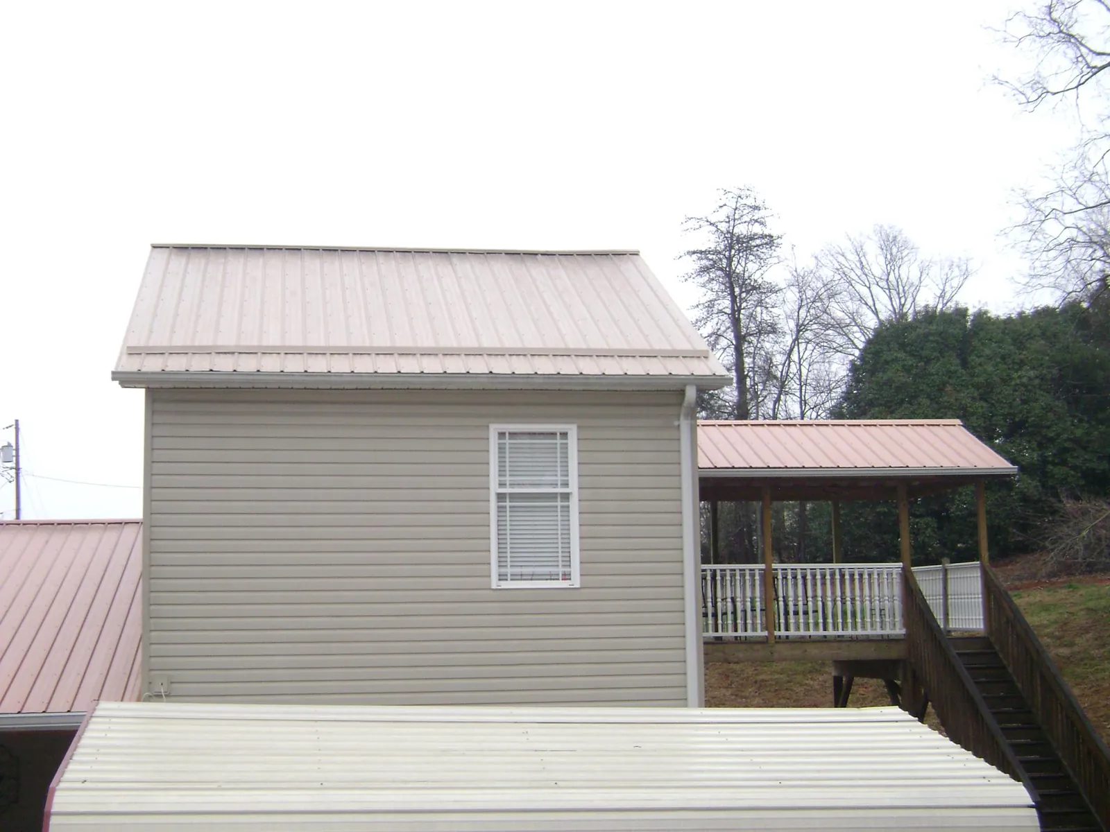 Tan metal roofs on a two story addition and attached porch, from a Roof Replacement job in Castleford