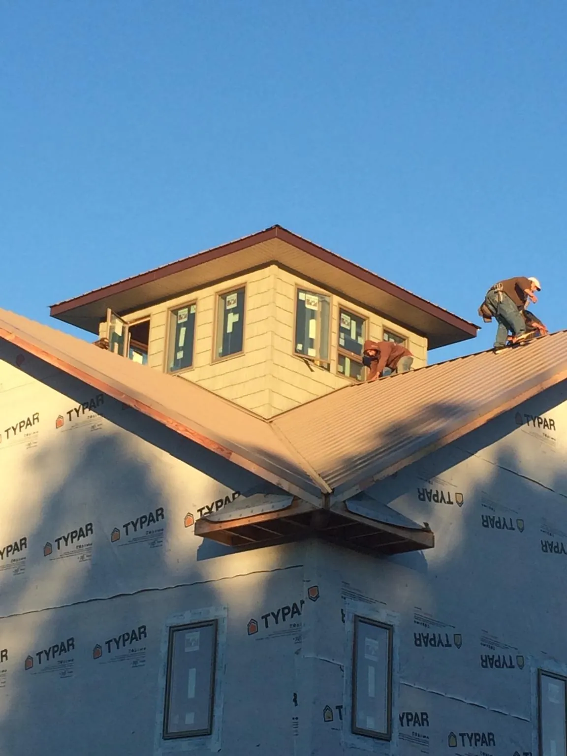 Roofers working around a rooftop cupola on a new metal roof at sunset — Roof Waterproofing in Castleford by Roofing Brothers